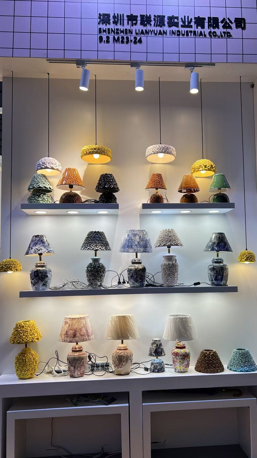 Shelves of ceramic table lamps with patterned and pleated shades under the Shenzhen Lianyuan Industrial sign