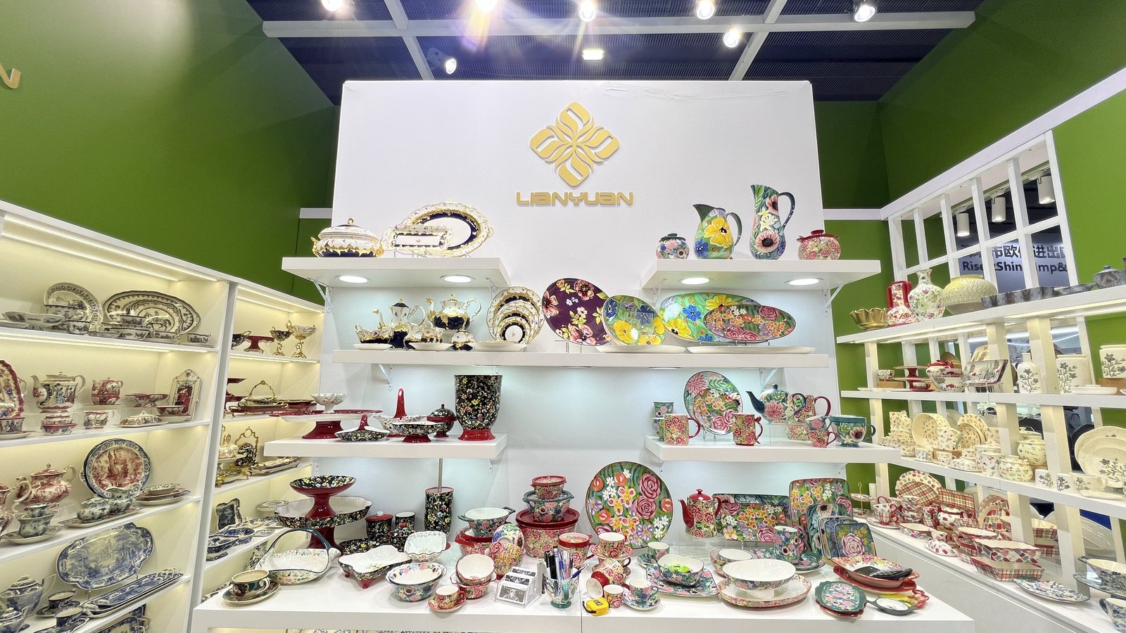 LianYuan stand with green walls and white shelves full of hand-painted plates, bowls and jugs